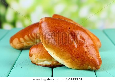 Empanadillas al horno frescos, en mesa de madera, sobre fondo brillante