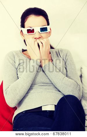 Sceared woman in 3d glasses is watching movie.