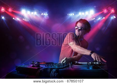 Handsome teenager dj mixing records in front of a crowd on stage