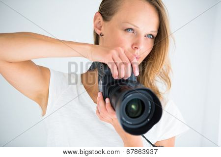 Pretty, female photographer with digital camera - DSLR and a huge telephoto lens (color toned image; shallow DOF)