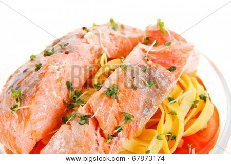 fresh fried natural pink salmon on italian traditional tagliatelle backed with tomato and vegetables isolated over white background
