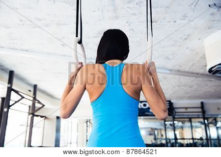Rear view portrait of woman working out on gimnastic rings at gym