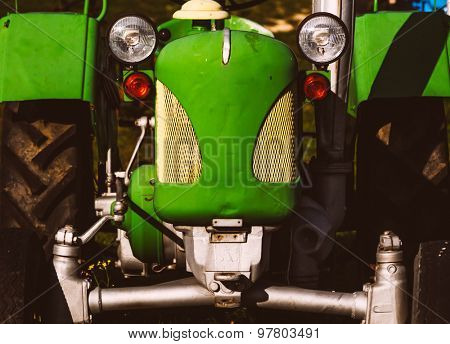 Old green tractor in field , retro toned photo
