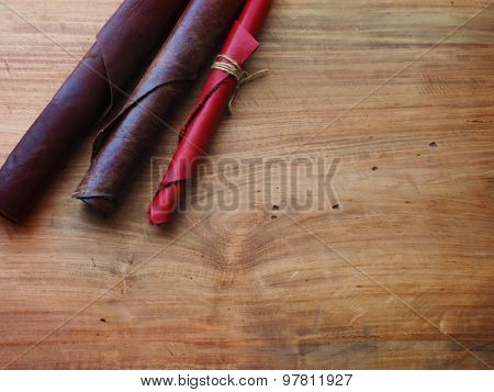 leather craft. Brown and red leather in rolls, on rustic work table. 