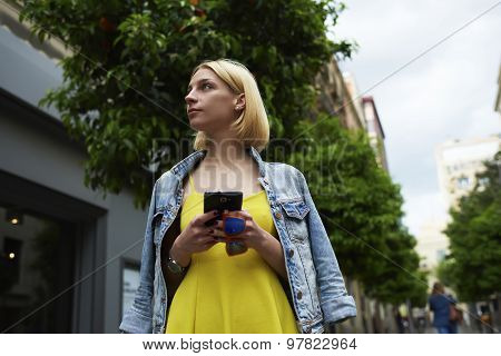Lost female tourist using telephone for navigation checking out the sights while standing outdoors