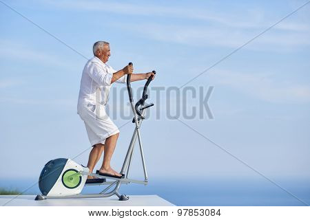 healthy senior man working out on gym treadmill machine at modern home terace with ocean view