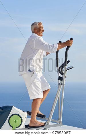 healthy senior man working out on gym treadmill machine at modern home terace with ocean view