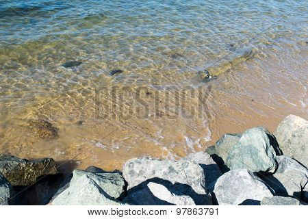 Sandy beach, tides and rocky boulders on shore