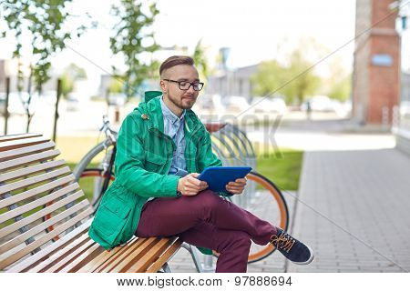 people, style, technology and lifestyle - happy young hipster man with tablet pc computer and fixie bike sitting on bench in city