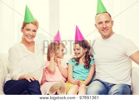 celebration, family, holidays, children and birthday concept - happy family with two chldren in hats celebrating