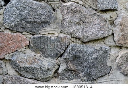 Old stone wall made of huge granite. Grunge design backdrop