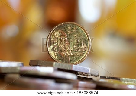 Australian two dollar coin on a bed of coins depicting an aboriginal man from the first nation.