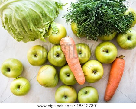 Two orange carrots green apples dill and cabbage on the table. Close-up view. View from above