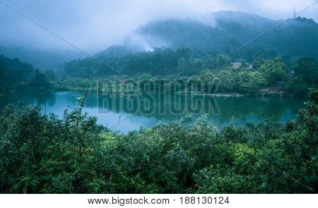 A small lake with clear water, mist surrounding the mountains. Wildflowers everywhere