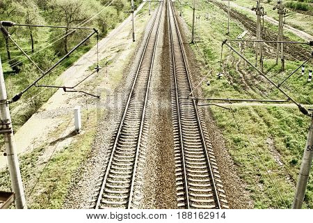 Empty railway tracks in a rural scene with grass and electric lines