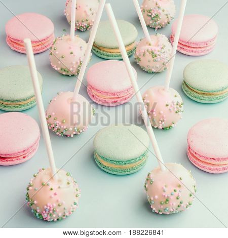 Close-up of colorful macaroons mixed with cake pops with icing on sticks