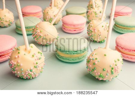 Closeup of colorful macaroons mixed with cake pops on sticks