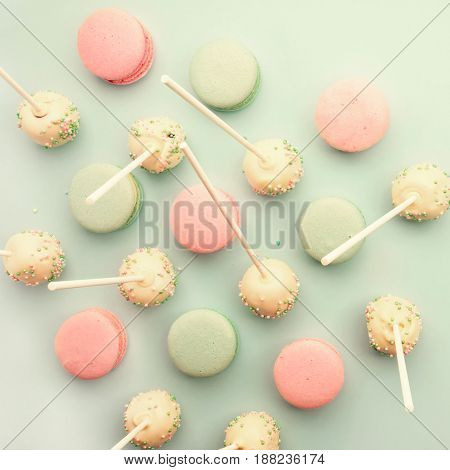 Colorful macaroons mixed with cake pops on sticks. Flat lay. Top view