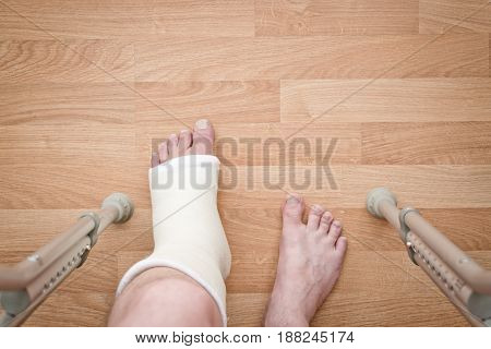 Leg in plaster and crutches on a wooden background