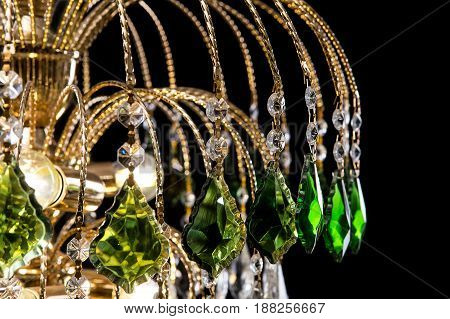 Chandelier for interior of the living room. chandelier details decorated with green crystals isolated on black background. Close-up photo