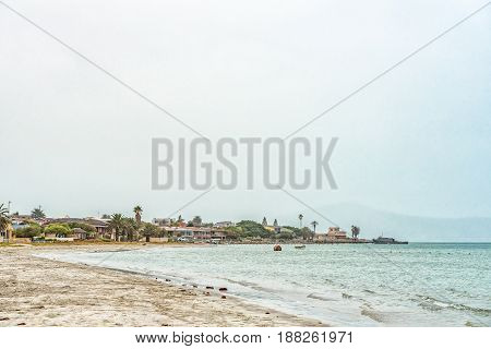 LANGEBAAN SOUTH AFRICA - MARCH 31 2017: Buildings in misty conditions on a beach with a ship at anchor at Langebaan on the Atlantic Coast of the Western Cape Province