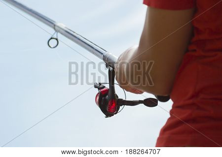 Fisherman catches a fish. Hands of a fisherman with a spinning rod in hand closeup. Spin fishing reel
