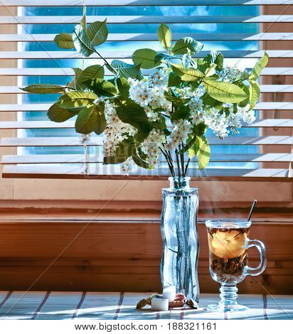 Cup of tea with emon and cherry on wooden background. Window. Spring
