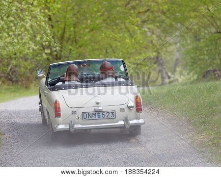 STOCKHOLM SWEDEN - MAY 22 2017: White BMC MG Midget ME 111 classic car from 1968 driving on a country road in the public race Gardesloppet in the forests at Djurgarden Stockholm Sweden. May 22 2017