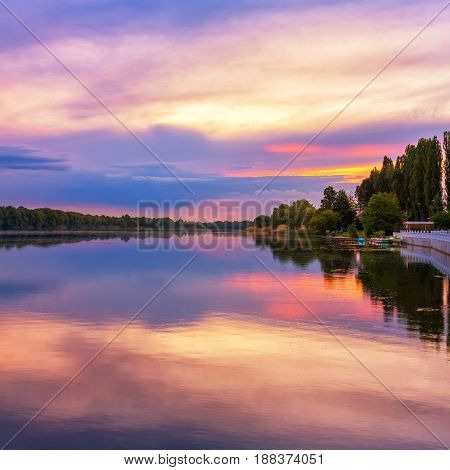 Vivid scenery of sunset at the river colorful dramatic evening sky reflected in the water hdr image. Khmelnytskyi Ukraine.