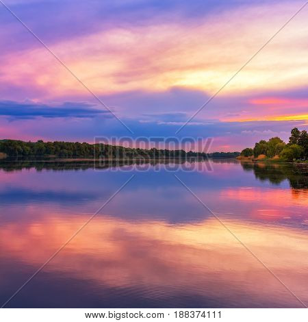 Vivid scenery of sunset at the river colorful dramatic evening sky reflected in the water hdr image. Khmelnytskyi Ukraine.