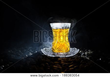 Turkish Azerbaijan Tea In Traditional Glasse And Pot On Black Background With Lights And Smoke. Armu