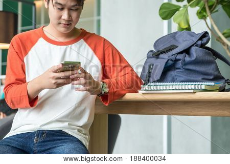 Young man asian teenager using mobile phone chatting with friends after class at university campusEducation concept.