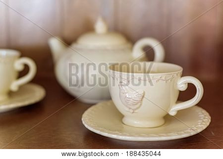 Teapot and cups with image of chicken on them are prepared for tea drinking in cafe