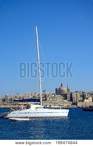 VALLETTA, MALTA - MARCH 30, 2017 - View of St Pauls Anglican Cathedral and the Basilica of Our Lady of Mount Carmel with a yacht in the foreground seen across the Grand Harbour from Sliema Valletta Malta Europe, March 30, 2017.