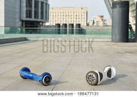 Two gyroboards on the pavement. White and blue hoverboards.  