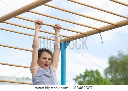 A Teenager In A T-shirt Is Engaged In Gymnastics On A Horizontal Bar