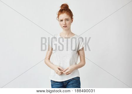 Cute shy redhead girl with hair bun looking at camera. Isolated on white background. Copy space.