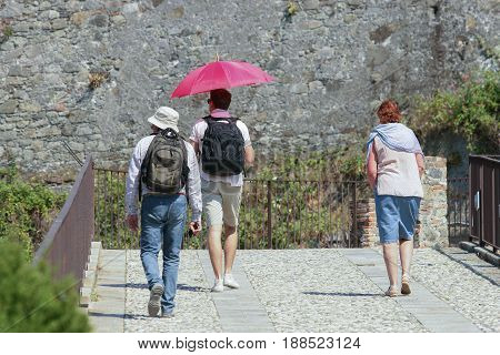 Vacationer travels in the sun by sheltering with a red umbrella