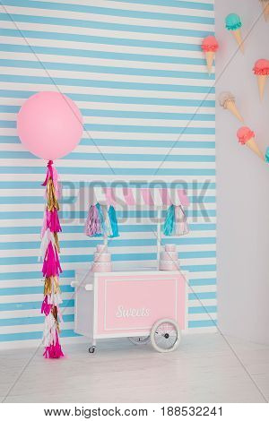 Children's zone with sweets: lollipops, ice cream, macarons, balloon and candy bar. Children room with blue stripe background.