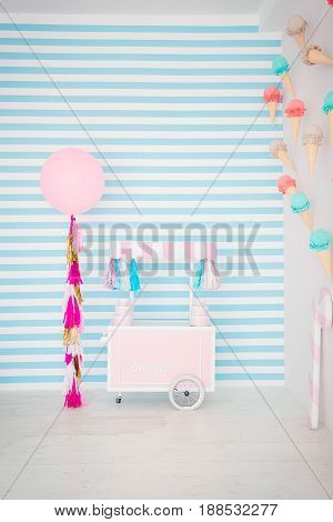 Children's zone with sweets: lollipops, ice cream, macarons, balloon and candy bar. Children room with blue stripe background.