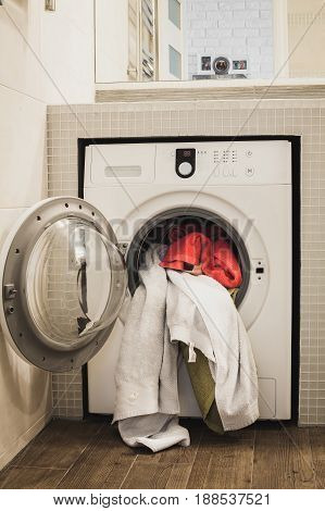 Washing machine with multicolored dirty towels inside. Vertical