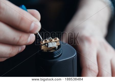 male master installs a coyle. Spiral for electronic evaporator and cigarette. Vape, vaping. Firing a coil.