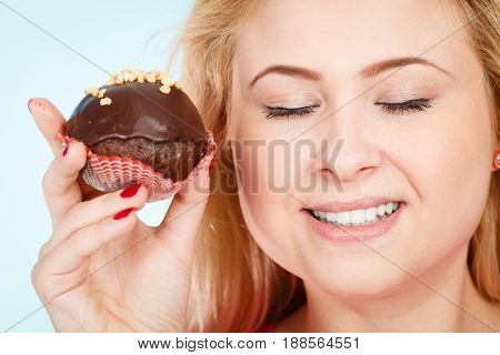 Diet sweets food concept. Woman holding delicious chocolate cupcake with peanut frosting about to take bite