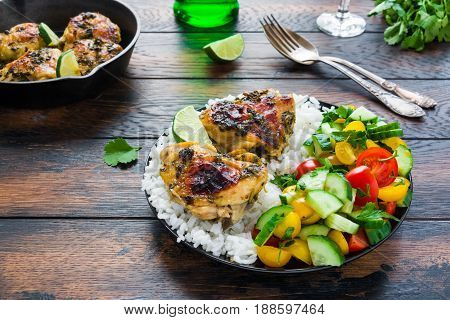 Healthy balanced dinner spicy and crispy homemade cilantro lime chicken thighs rice and salad with fresh vegetables.