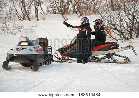 Murmansk, Russia - February 15, 2010: The driver of a snowmobile indicates the way to another friend