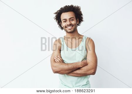 Handsome happy african man smiling posing with crossed arms over white background. Copy space.