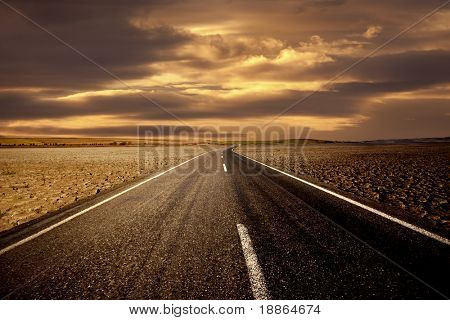 Straße auf trockenem Land und dem goldenen Himmel