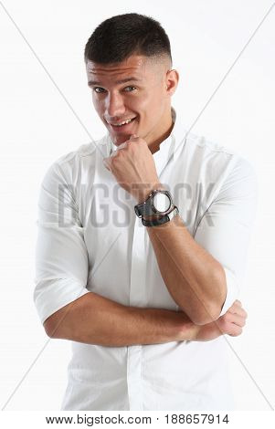 A Man Holds His Hand To His Chin Against A White Background. Looks At The Camera And Smiles