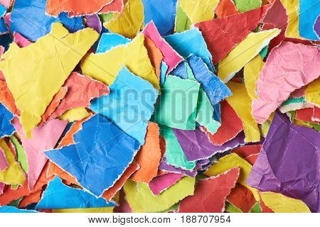 Surface covered with multiple colorful pieces of torn paper as an abstract background composition