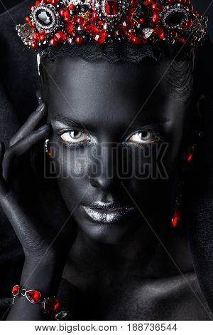 Jewelry industry. Fashion portrait of a beautiful young woman with perfect black skin wearing diadem with rubies and other precious stones. Jewelry and bijouterie. Body painting project.